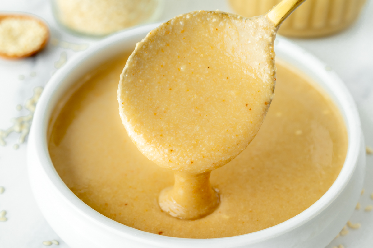 tahini dripping off of spoon into bowl