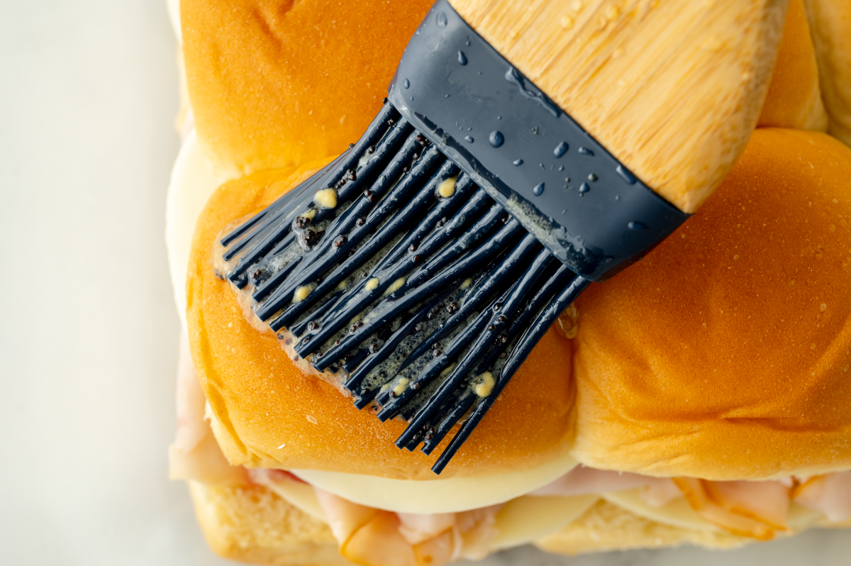 close up of pastry brush adding sauce to buns