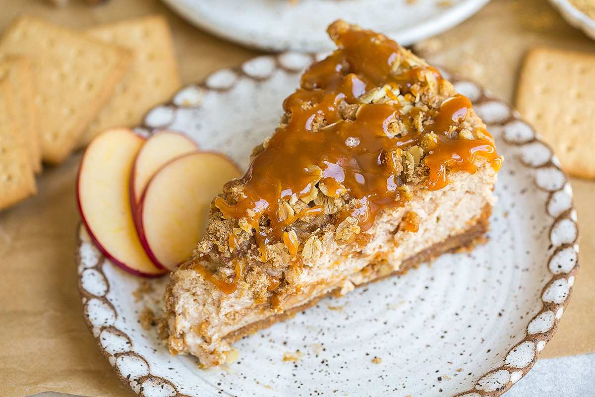 close up angled shot of slice of apple pie cheesecake on plate