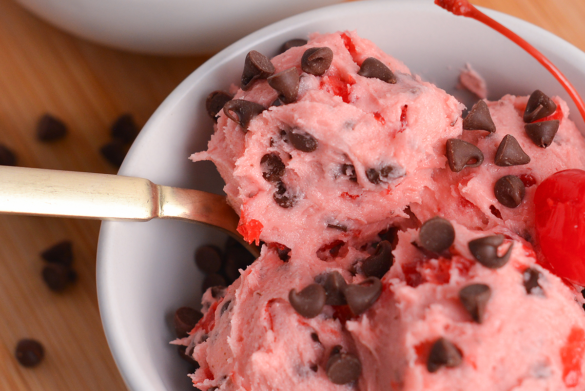 close up of spoon in bowl of chocolate cherry cookie dough