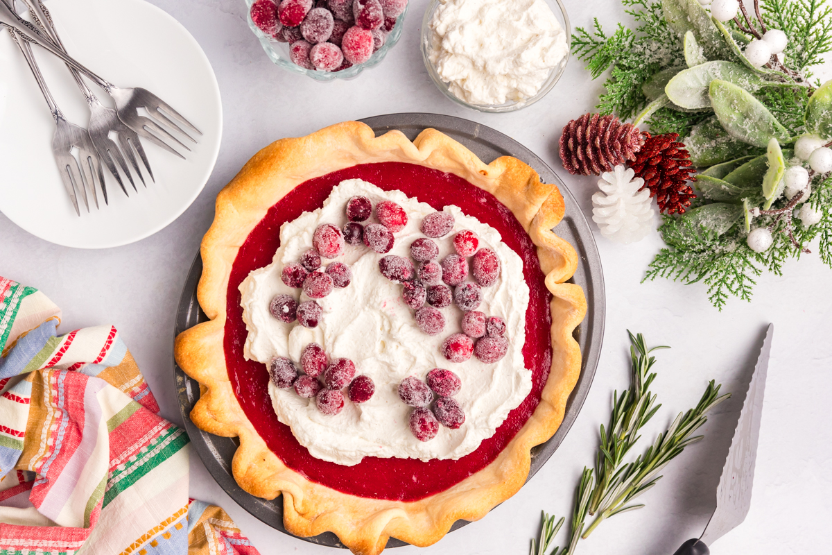 overhead shot of cranberry pie topped with whipped cream and cranberries