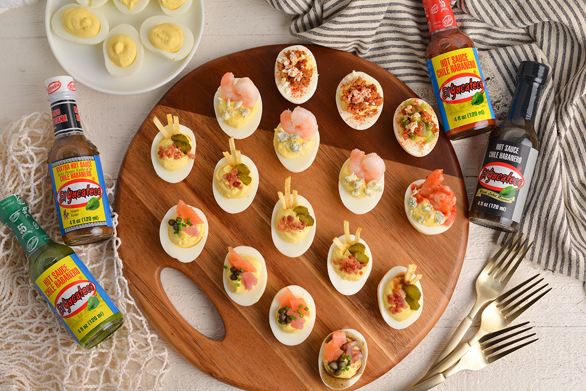 wide angle board of deviled eggs with hot sauce bottles