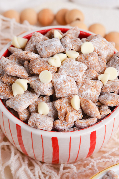 angled shot of white and red bowl full of cinnamon puppy chow