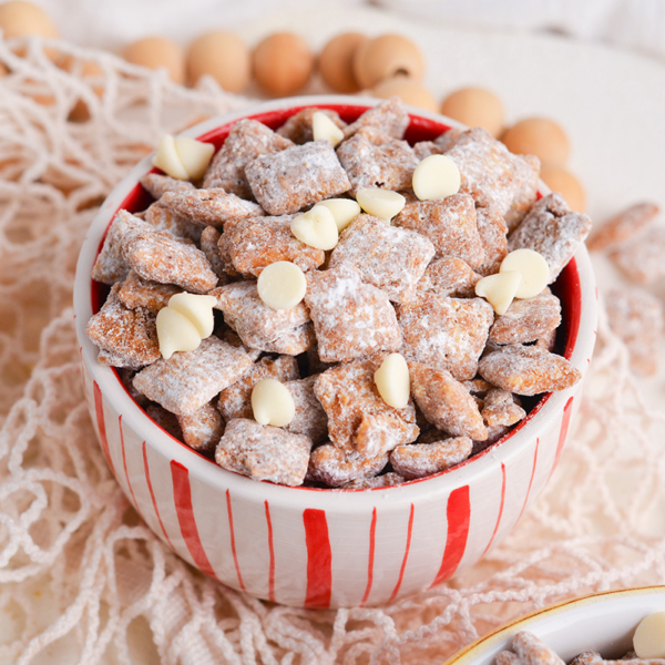 angled shot of white and red bowl full of cinnamon puppy chow