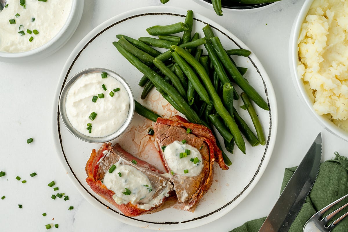 overhead shot of plate of steak and green beans with ramekin of sauce