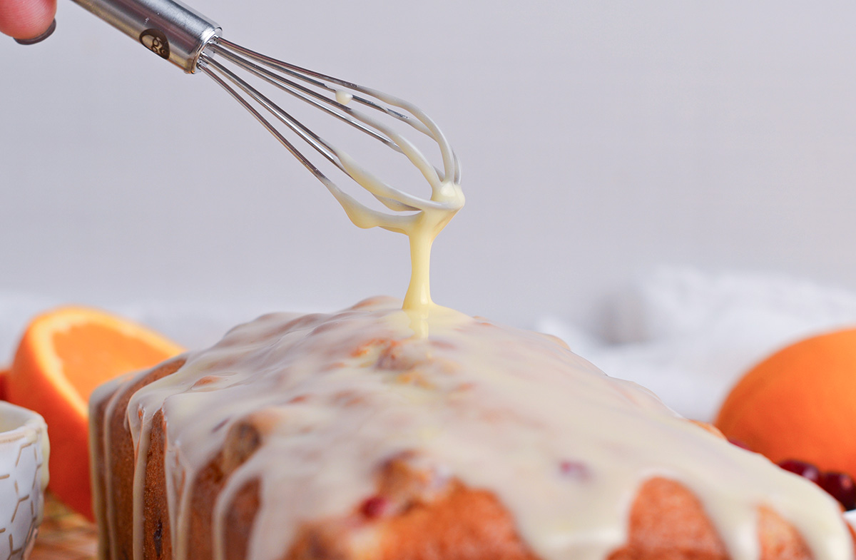 orange glaze dripping onto cranberry bread loaf