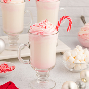 straight on shot of white hot chocolate topped with whipped cream with candy cane