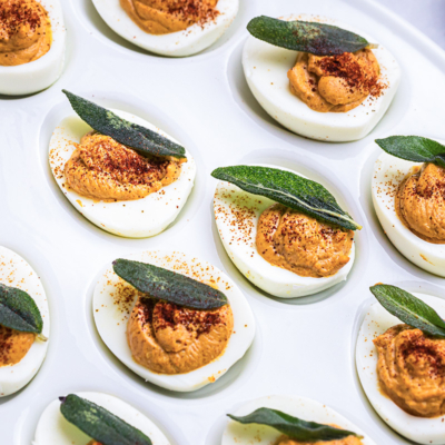 angled shot of platter of deviled eggs topped with sage leaves