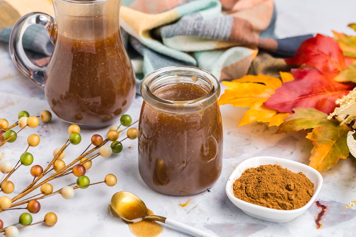 angled shot of jar of pumpkin spice syrup with bowl of cinnamon