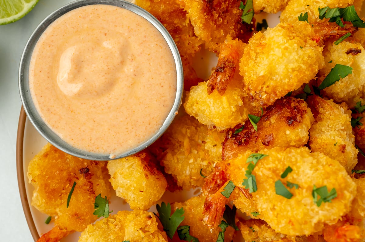 close up overhead shot of fried shrimp with ramekin of red curry sauce