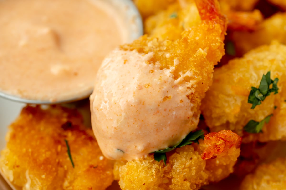 close up of fried shrimp dipped into sauce