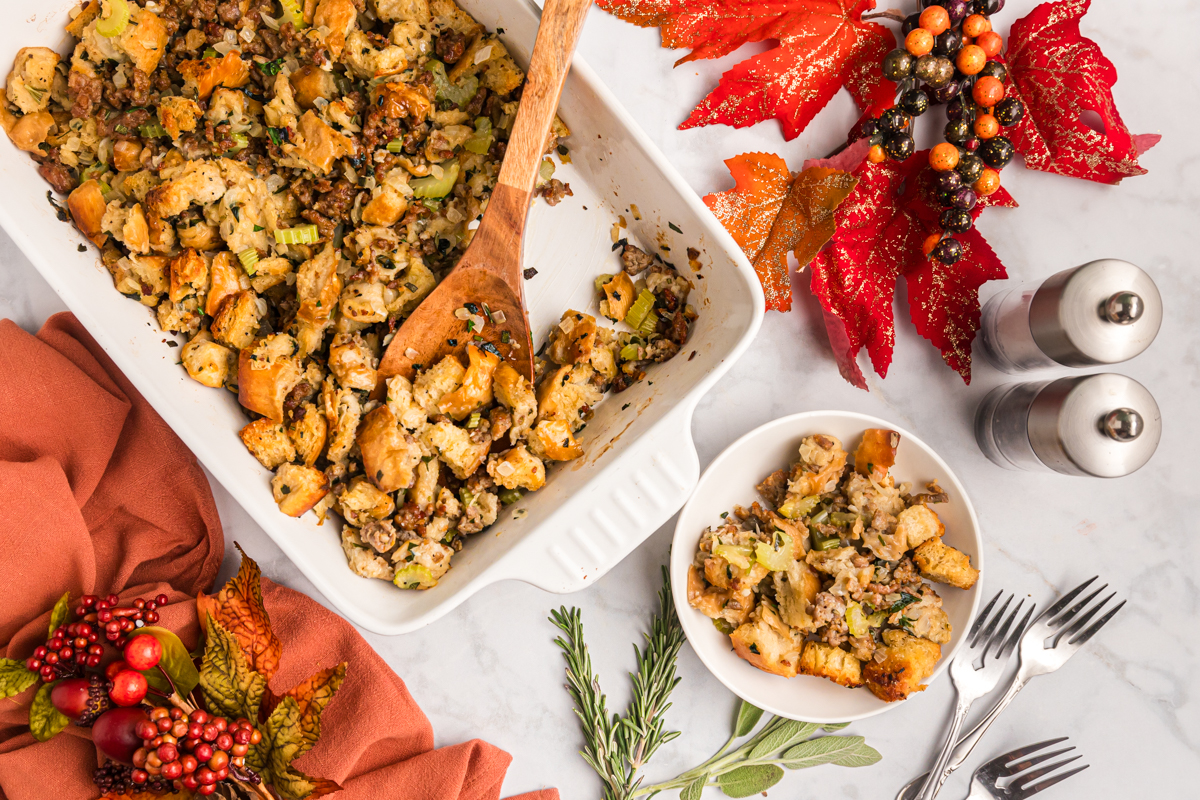 wooden spoon in baking dish of sausage stuffing