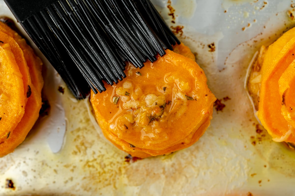 close up of butter brushing onto sweet potato stack