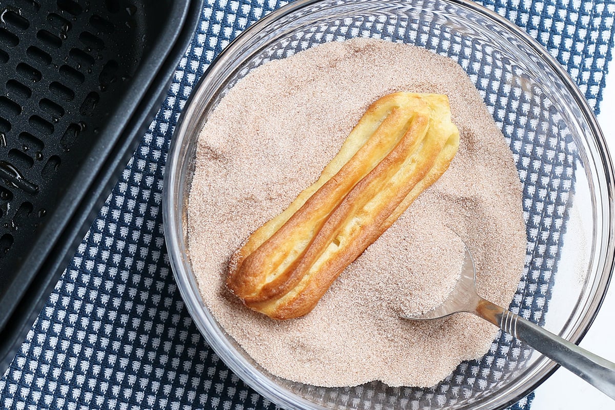 air fryer churro in bowl of cinnamon sugar