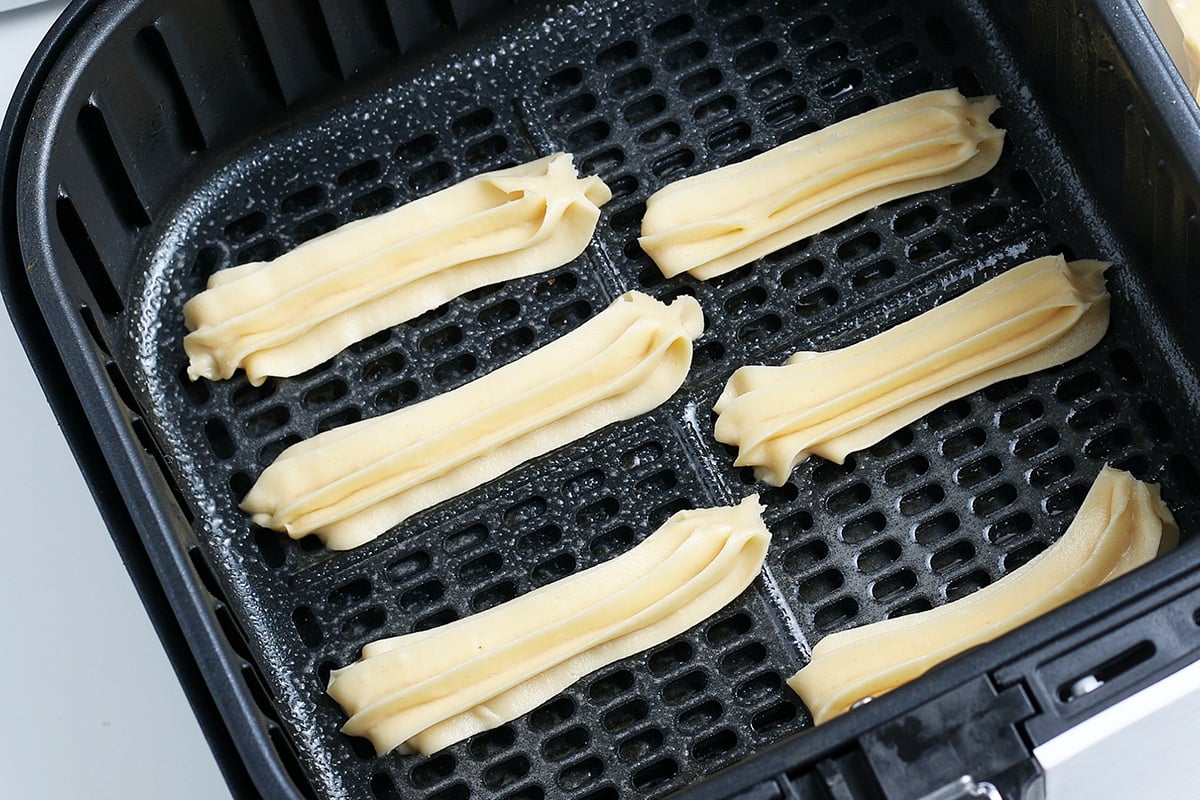 churro dough piped into air fryer basket