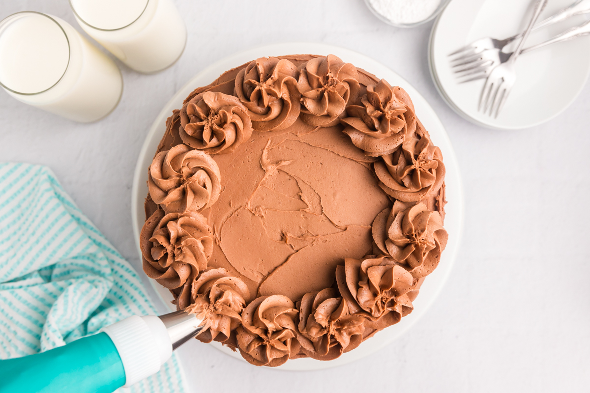 overhead shot of piping bag adding frosting to cake