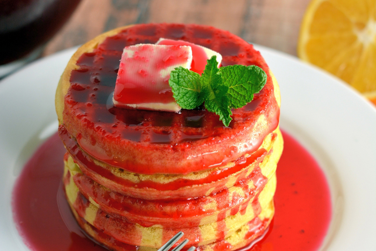 stack of waffles topped with cranberry syrup