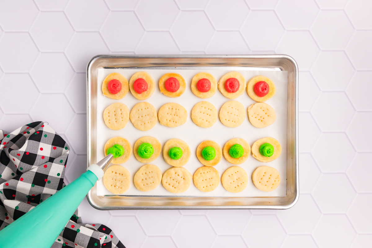 piping bag added icing to circular cookies