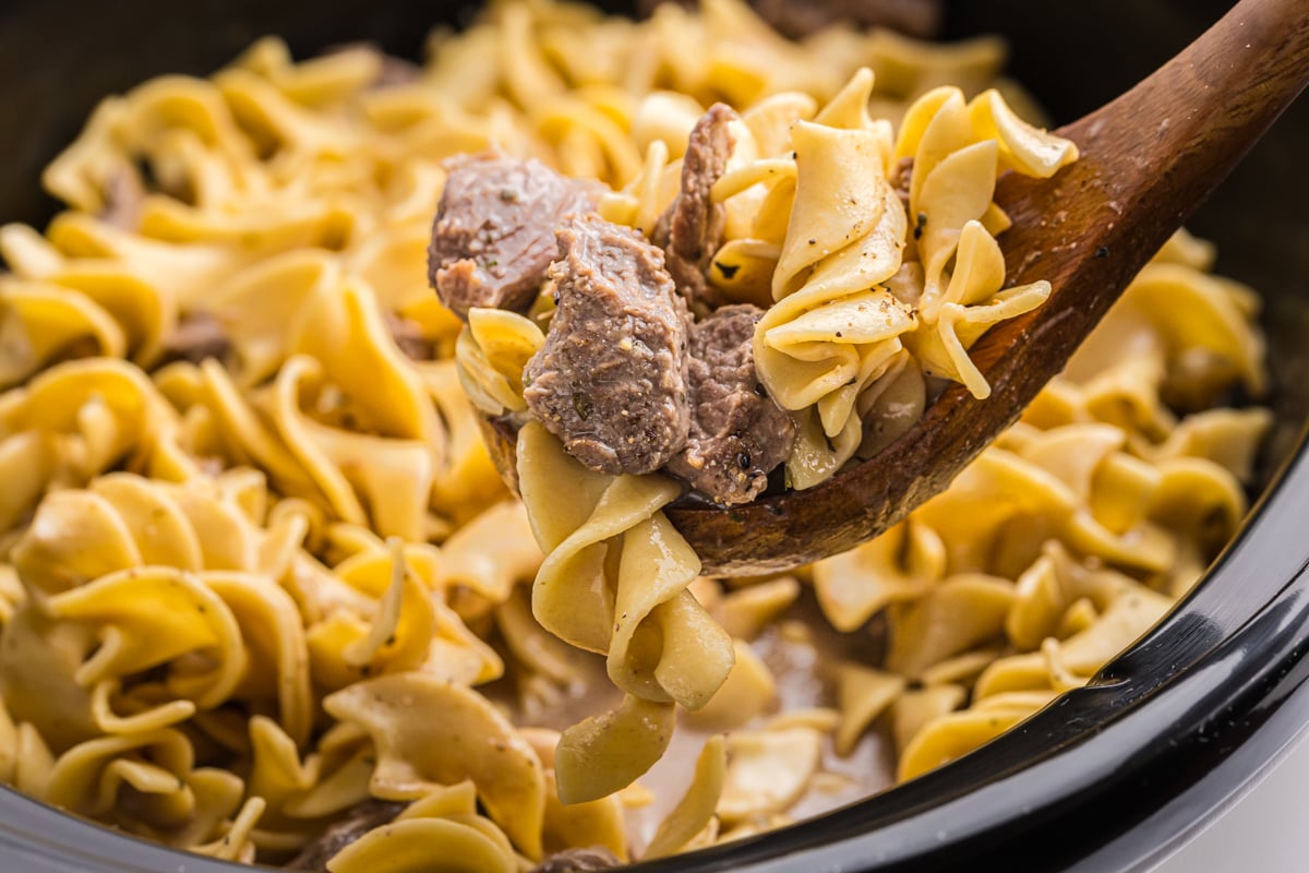 angled shot of ladle full of crock pot beef and noodles