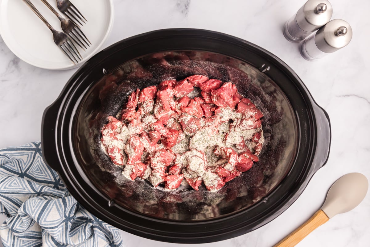 cubed beef and seasoning in a crock pot