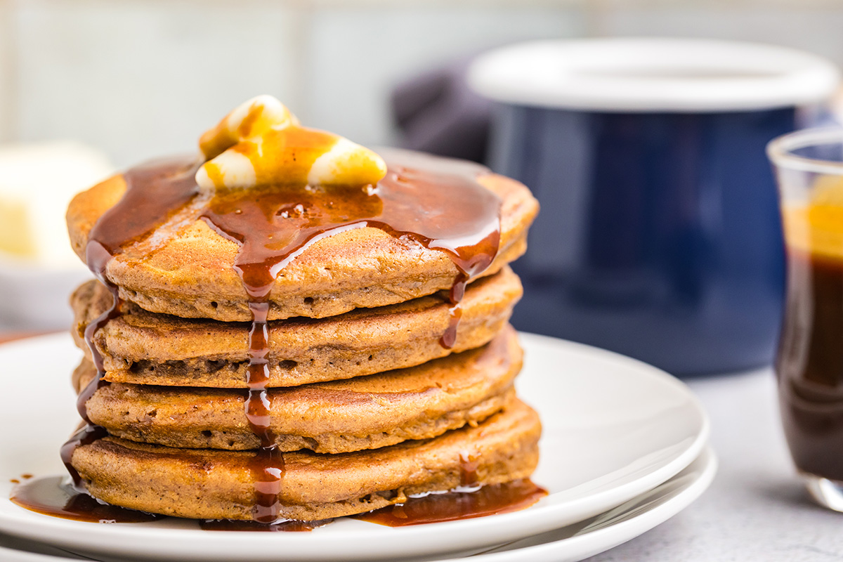 close up straight on shot of butter and syrup over stack of gingerbread pancakes