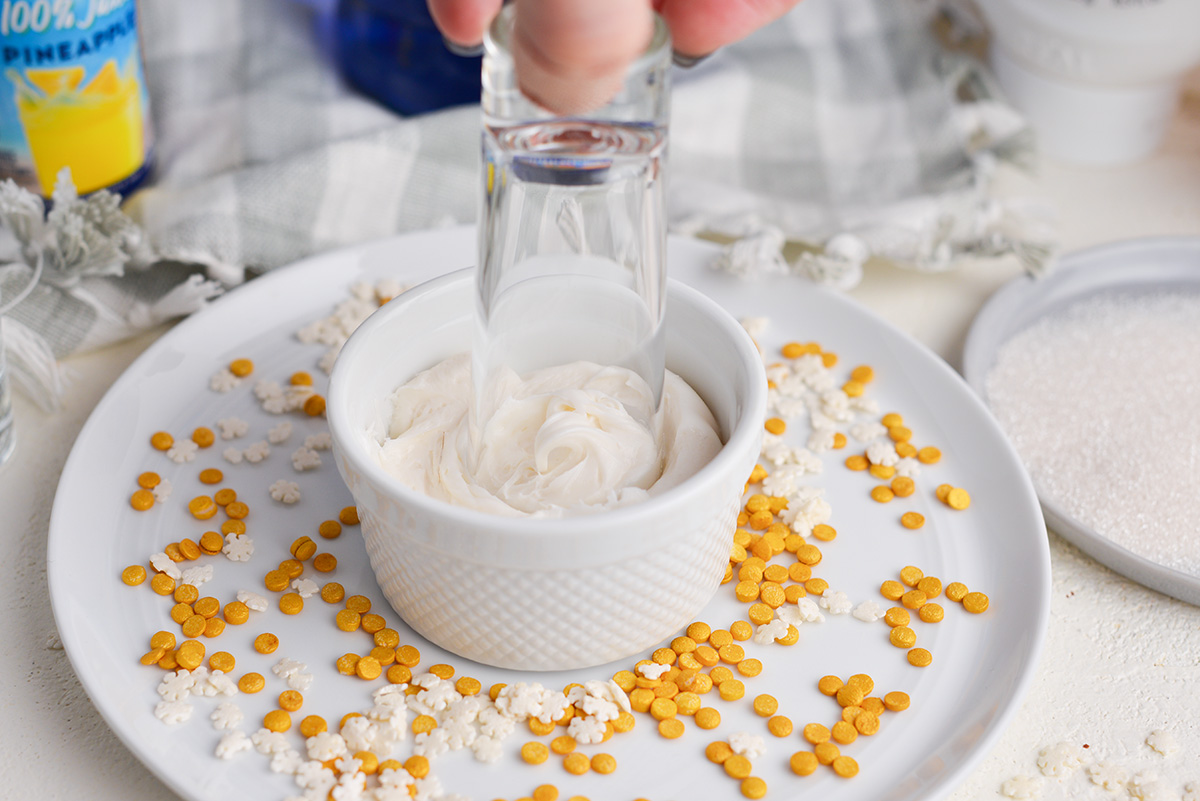 shot glass dipping into bowl of frosting