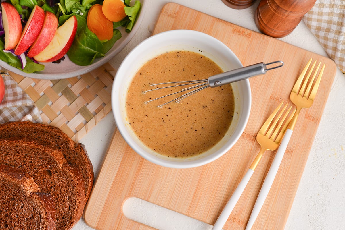 overhead shot of whisk in bowl of maple dijon dressing