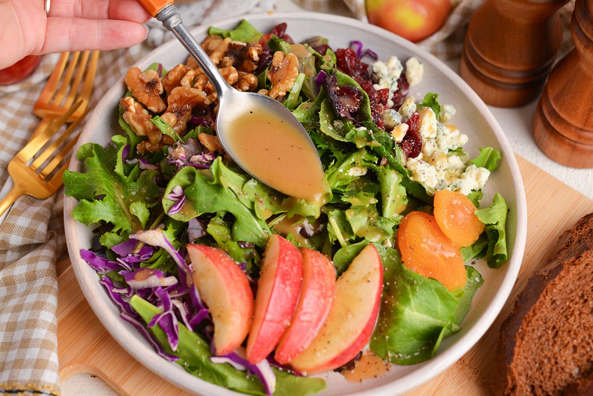 overhead shot of spoon adding dressing to salad