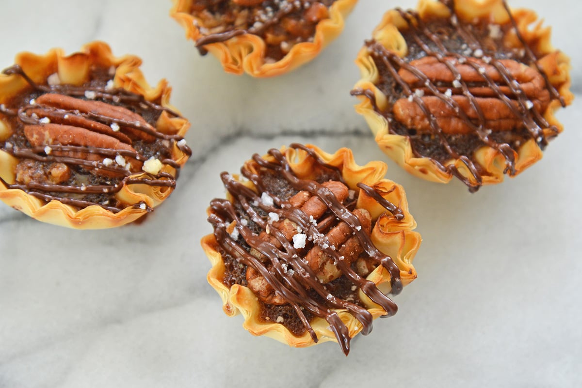 close up overhead shot of chocolate frizzled over mini pecan pies