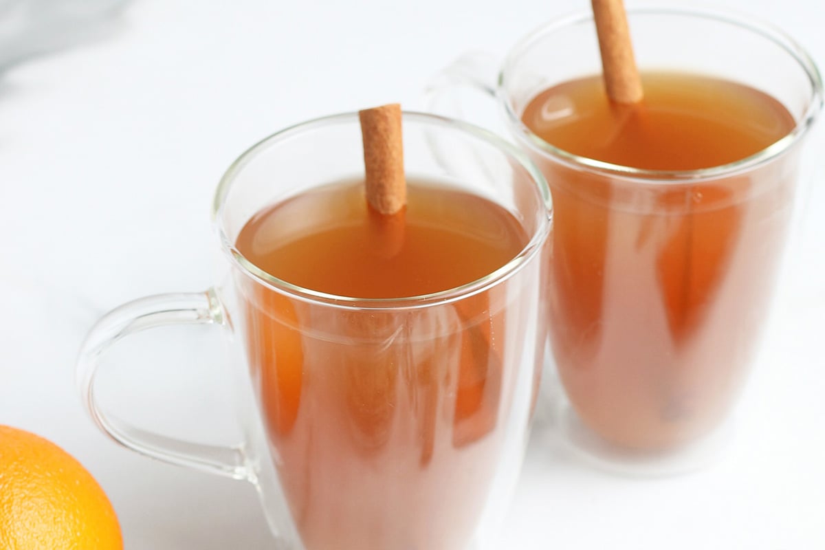 angled shot of two mugs of mulled cider