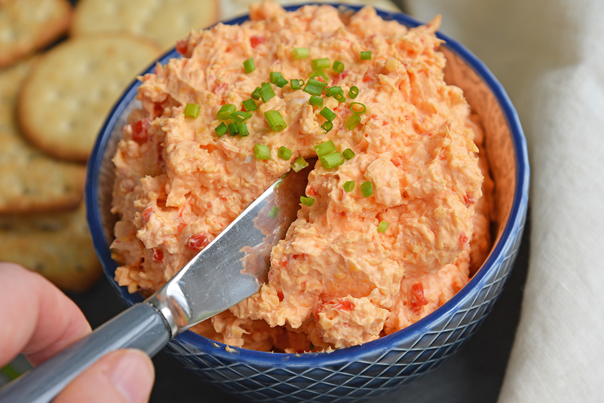 angled shot of knife in bowl of pimento cheese