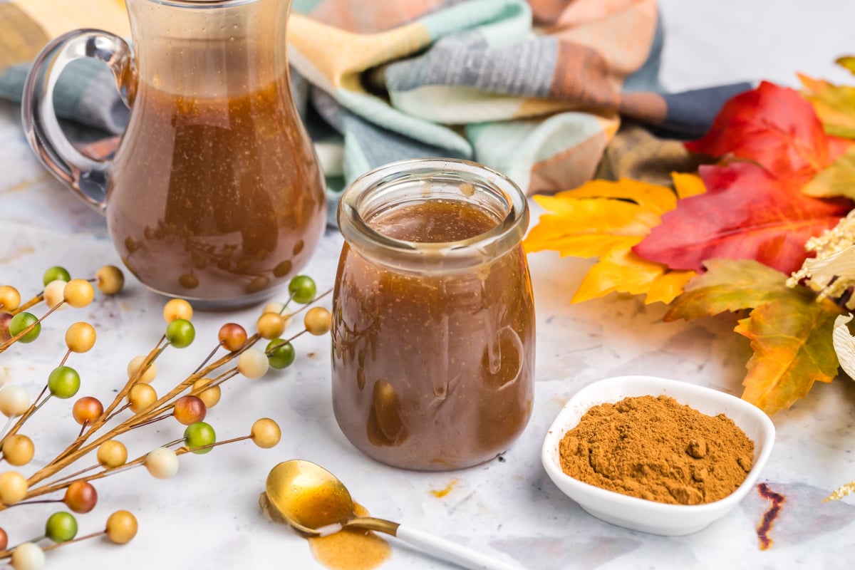 angled shot of jar of pumpkin spice syrup with bowl of cinnamon