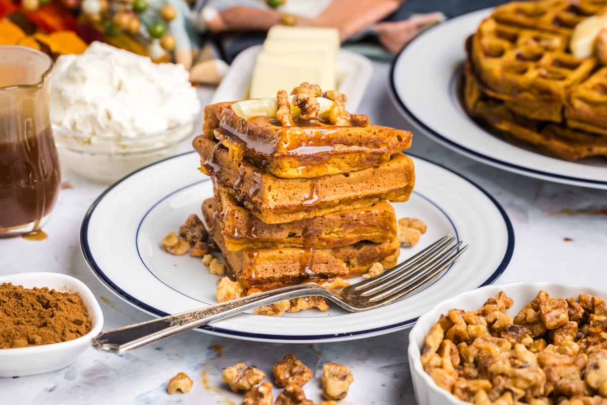 stack of pumpkin waffles on plate with syrup