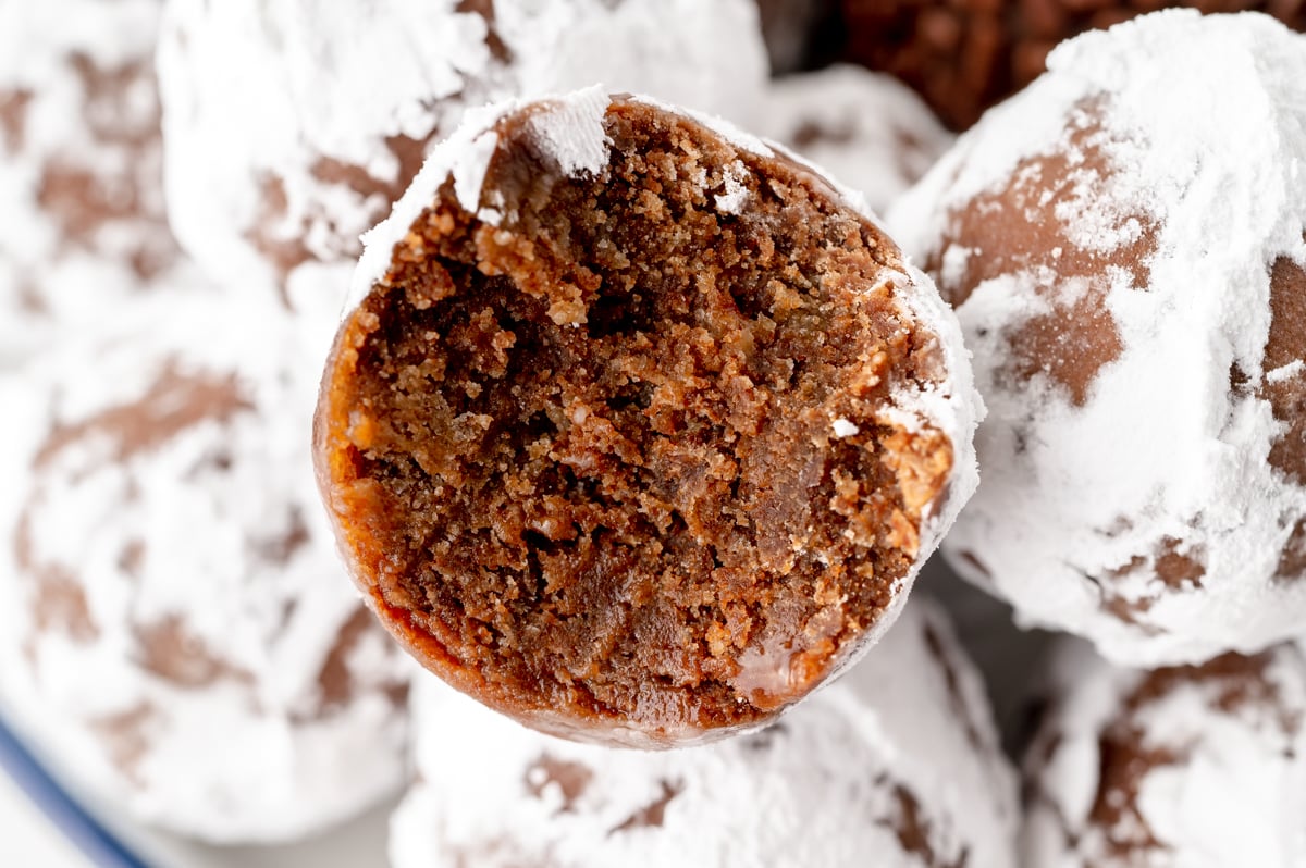 close up overhead shot of bite taken out powdered sugar coated rum ball