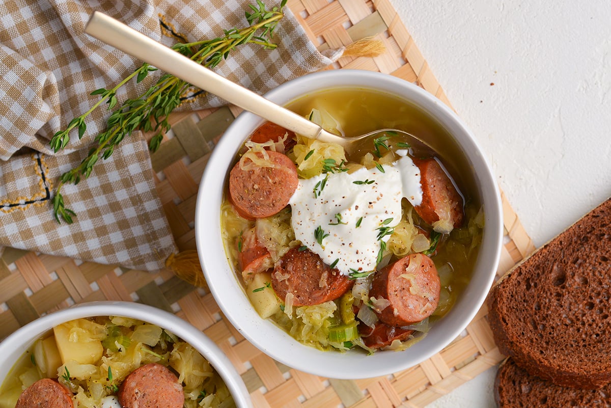 overhead shot of bowl of sausage and sauerkraut soup with a spoon in it