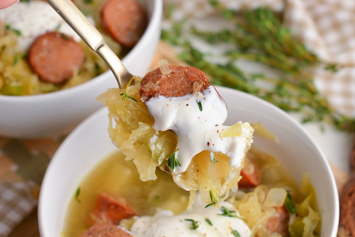 close up shot of spoon full of sausage and sauerkraut