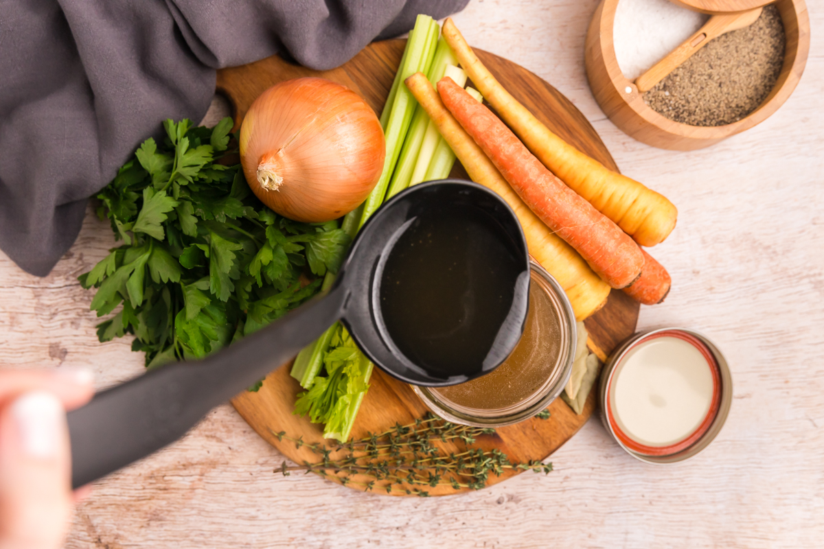 overhead shot of ladle pouring stock into jar