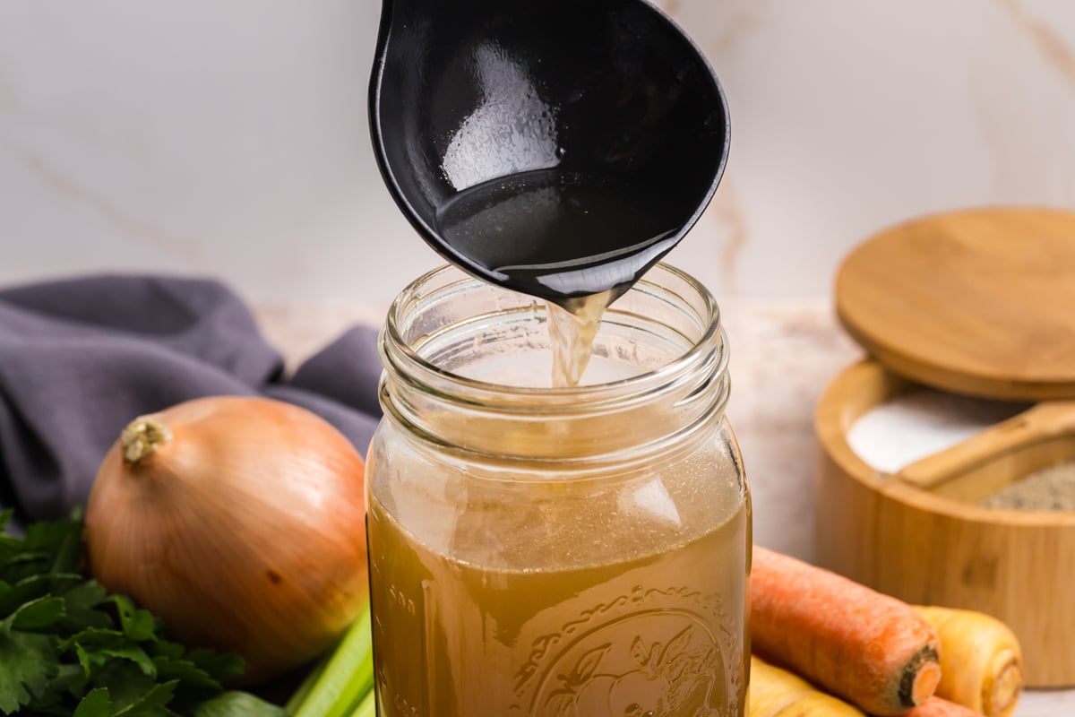 straight on shot of ladle adding stock to mason jar