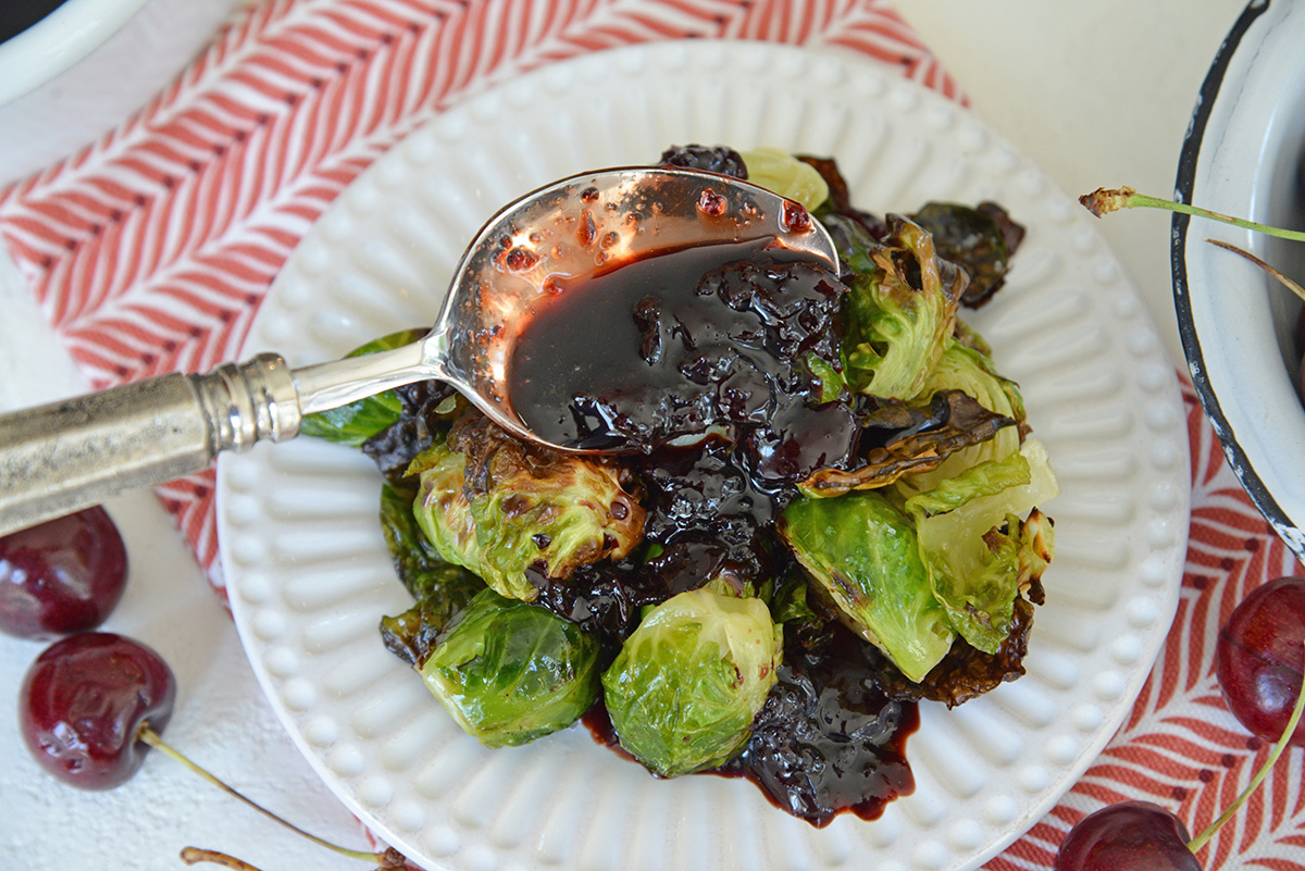 spooning balsamic sauce over brussels sprouts