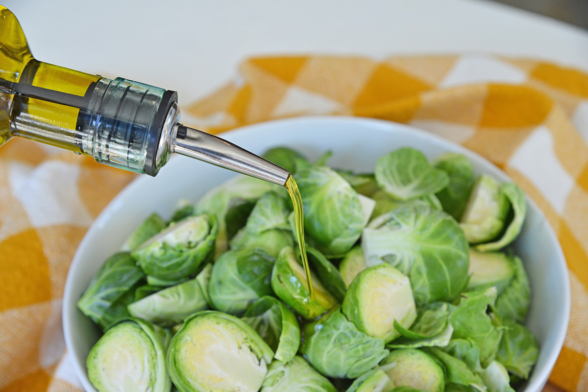 olive oil pouring onto fresh brussels sprouts