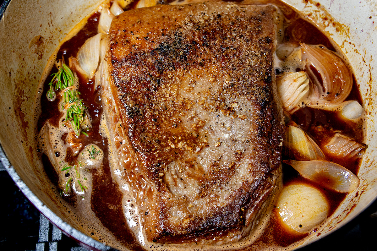 overhead shot of slow braised brisket cooking in dutch oven