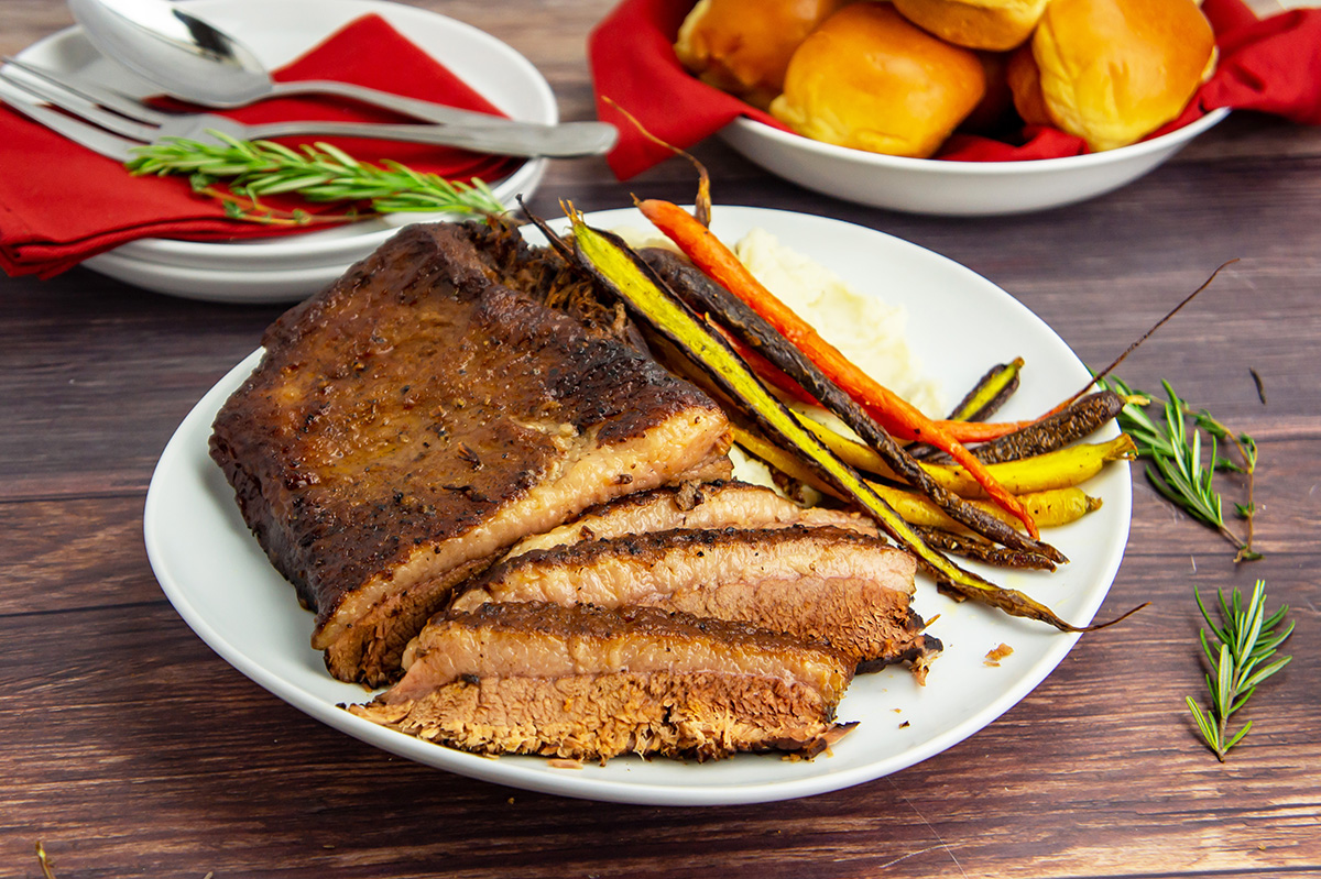 angled shot of sliced brisket on plate with carrots