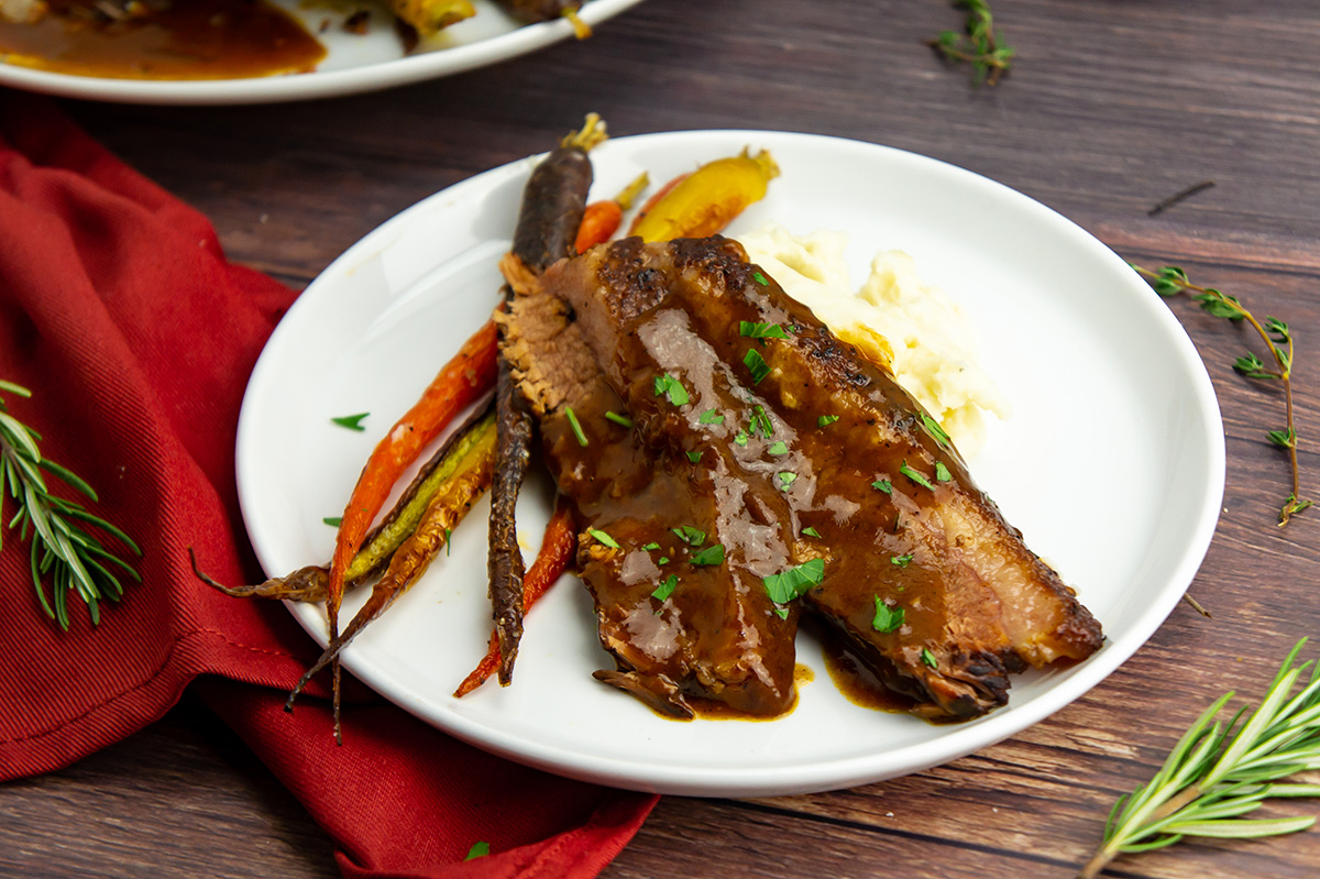 slices of slow braised brisket on plate with carrots