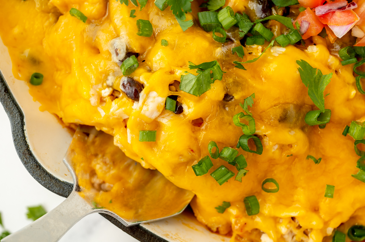 close up overhead shot of serving spoon in cheesy casserole