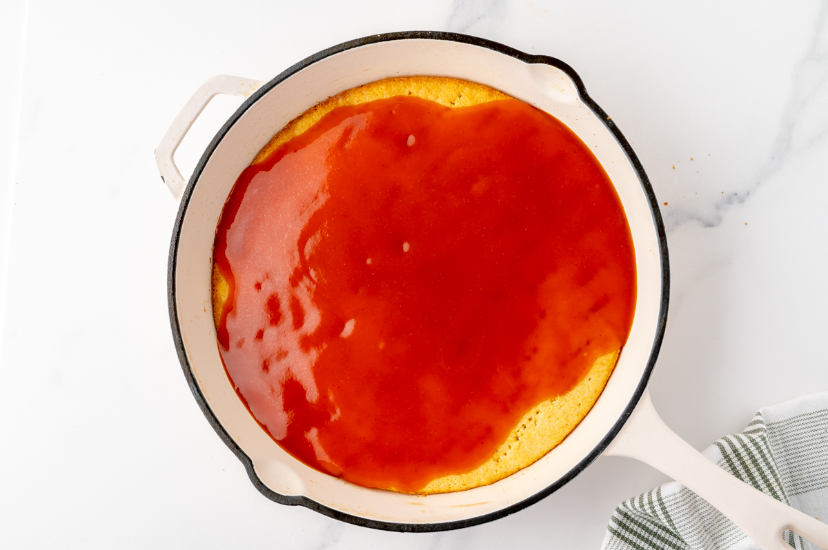 overhead shot of red enchilada sauce over cornbread