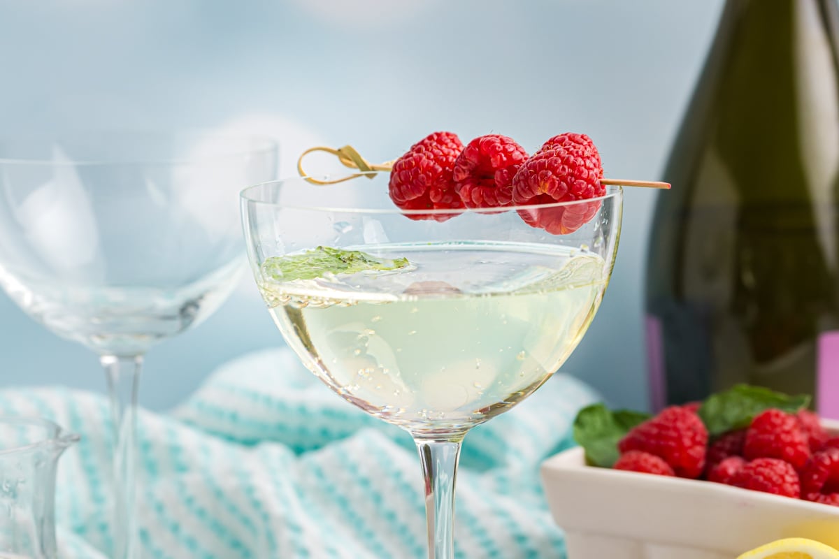 straight on shot of raspberries on glass of elderflower spritz