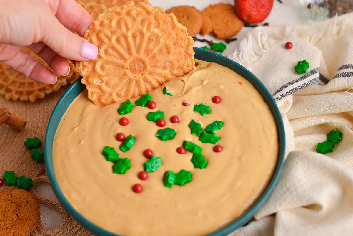 angled shot of pizzelle dipping into gingerbread dip