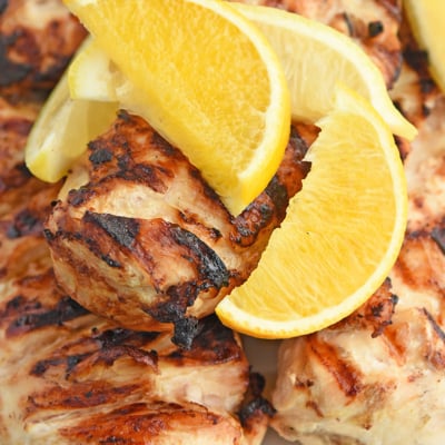 close up overhead of grilled chicken topped with citrus wedges