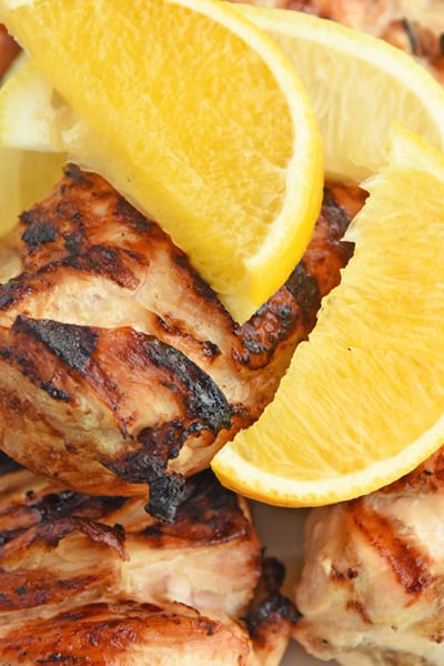 close up overhead of grilled chicken topped with citrus wedges