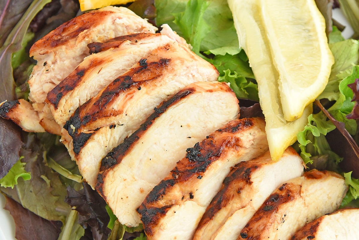 close up of sliced chicken over salad